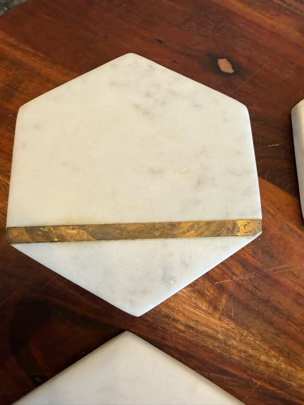 Hexagonal white marble coasters featuring a brass inlay design
